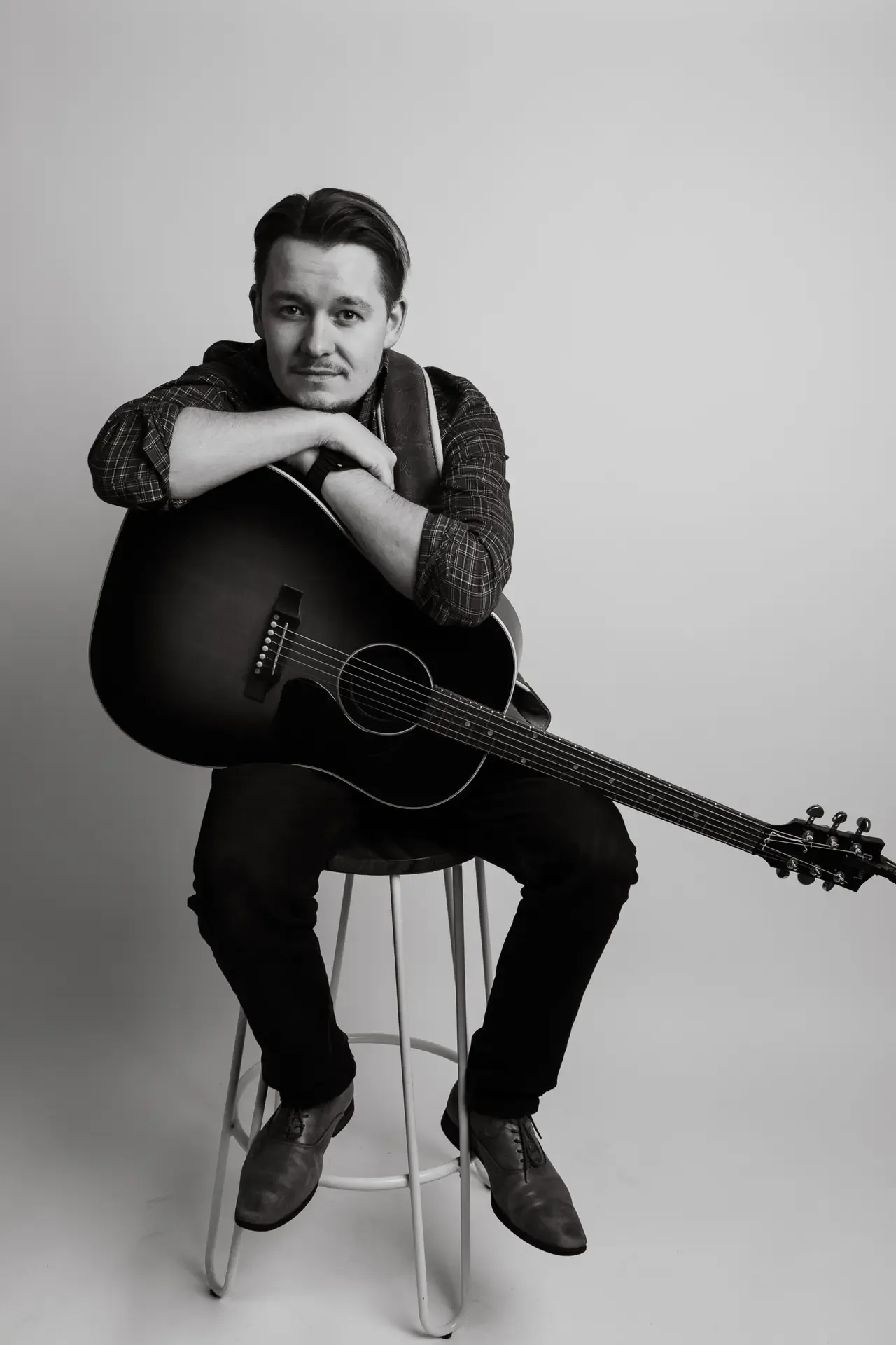 Daniel resting his elbows on his guitar