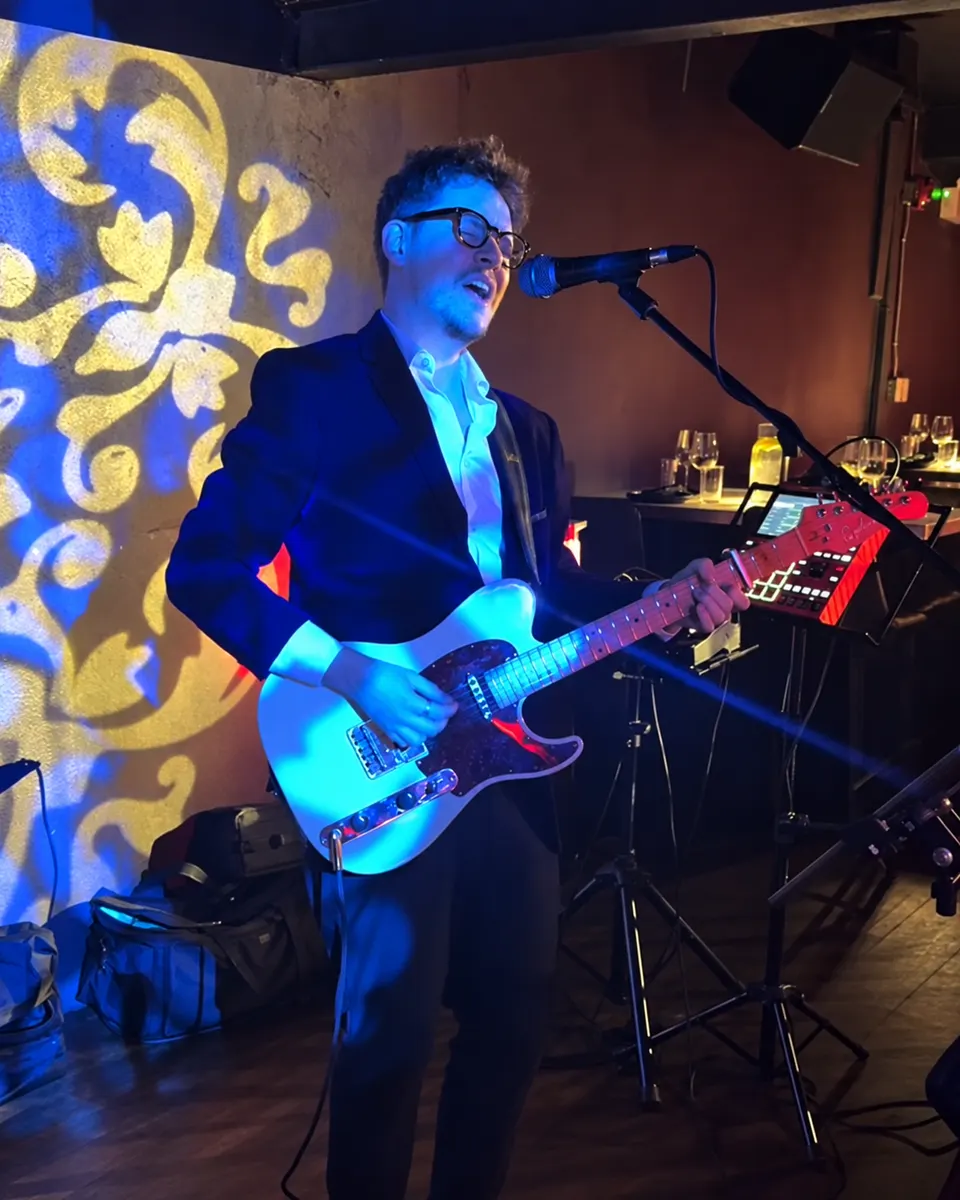 Daniel Humphreys singing and playing electric guitar in a blazer