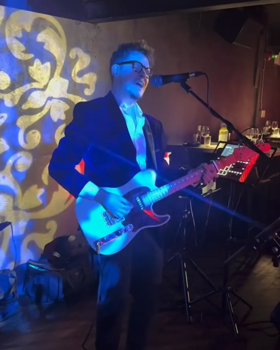 Daniel Humphreys singing and playing electric guitar in a blazer