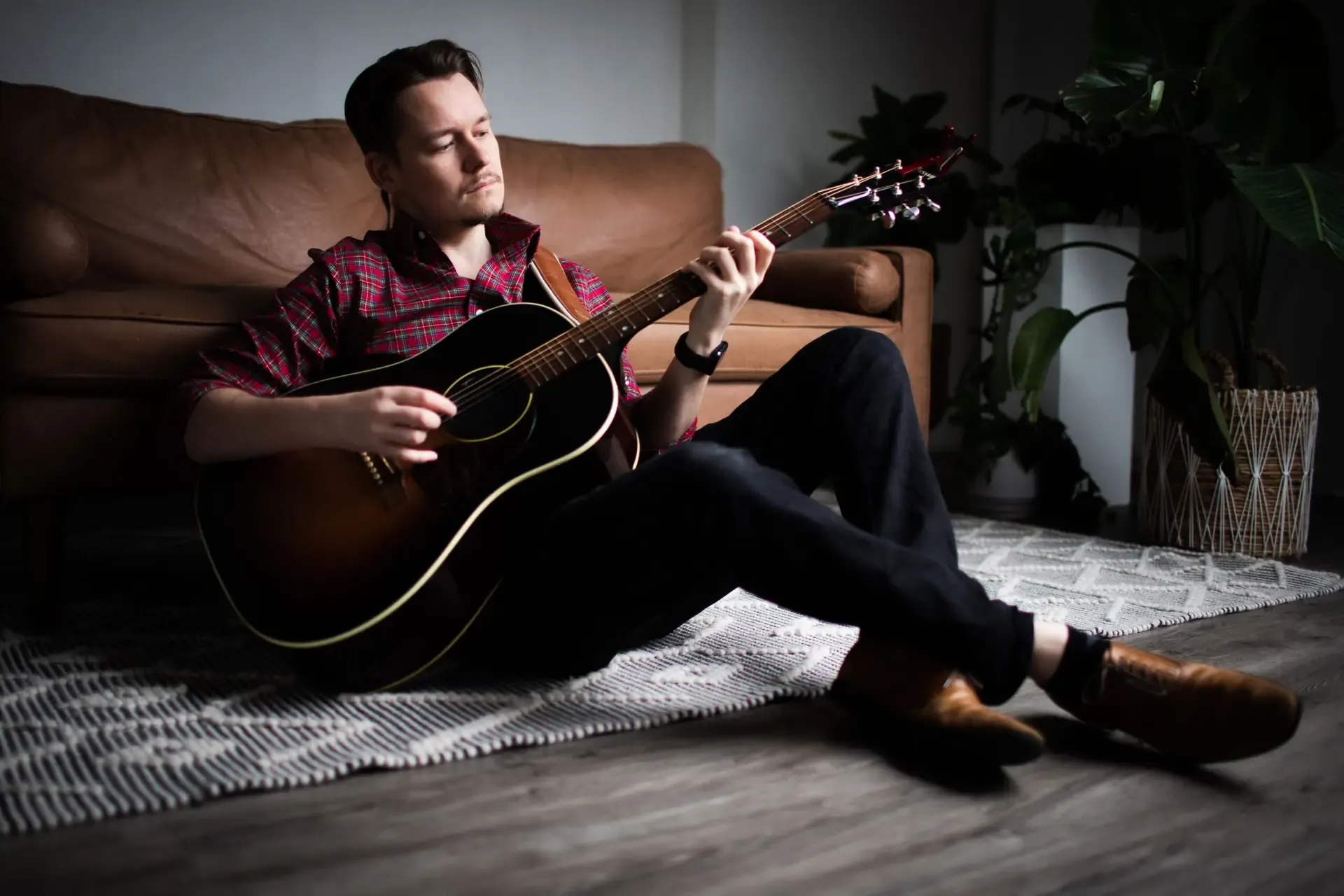 Daniel playing acoustic guitar on a couch